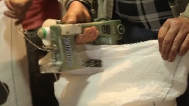 Man sews a sack of grain sewing machine — Stock Video