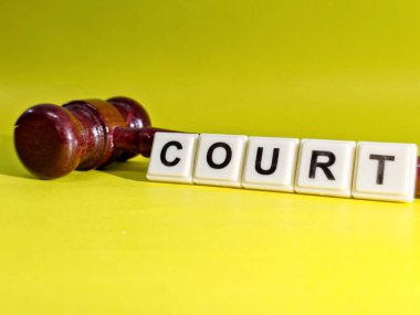 Tahta bir yargıç tokmağı beyaz fayansların yanında, parlak sarı bir arkaplan üzerine 