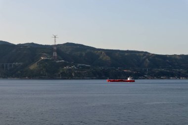Messina, Sicilya, İtalya - 23 Ağustos 2020: Gündoğumunda Messina Boğazı 'ndan geçen kırmızı kargo gemisi