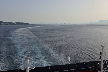 Messina, Sicilya, İtalya - 23 Ağustos 2020: Güneşin doğuşunda Messina Boğazı 'nı geçerken feribottan Sicilya kıyılarına bakış