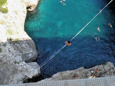 Santa Maria di Leuca, Lecce, Puglia, İtalya - 27 Ağustos 2019: Ciolo Kanalı 'nda ipten sallanan çocuk