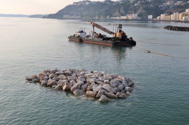 Bagnoli, Campania, İtalya, 28 Şubat 2026: Kuzey İskelesi 'nden daha sonra İtalyan olarak görülen eski Ilva çelik fabrikasının önündeki kıyı şeridi boyunca yeniden inşa ve güvenlik çalışmaları.