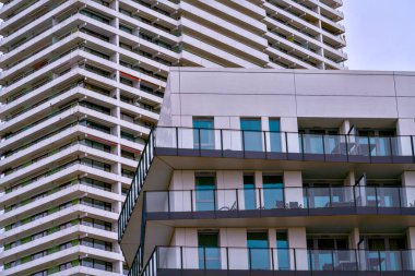 Renkli cam paneller ve şehir terası ritmiyle kaplı katmanlı balkon cephesi, emlakçı turkuaz parlatıcısını ön plana çıkarıyor.,