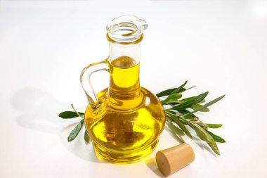 Beyaz arka planda zeytin yapraklı bir şişe zeytin yağı.