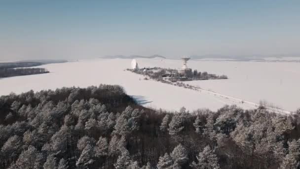 Filmisk antenn syn på rymdkommunikationsstationen i snötäckta fältet på solig vinterdag, drönare flygning över strategiskt objekt — Stockvideo