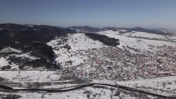 Αεροφωτογραφία της ανεμοστρόβιλος στο χιόνι που καλύπτει το τοπίο και τη μικρή πόλη σε ηλιόλουστη μέρα του χειμώνα, υψηλής ποιότητας βίντεο 4k — Αρχείο Βίντεο