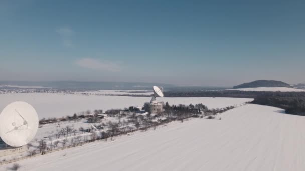 Widok z lotu ptaka na stację komunikacji kosmicznej w pokrytym śniegiem polu w słoneczny zimowy dzień, lot dronem nad obiektem strategicznym — Wideo stockowe