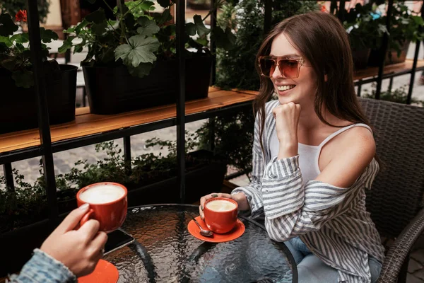 Dos mujeres jóvenes tomando café en un café al aire libre, concepto de la hora del almuerzo, chica morena en foco —  Fotos de Stock