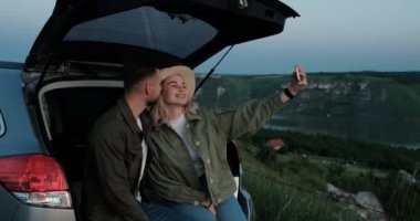 Erkek ve Kadın Araba Bagajında Oturuyor, Akıllı Telefon, Seyahat ve Yolculuk Konseptinde Selfie Çekiyor