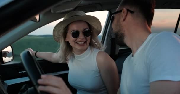 Feliz pareja joven sentada dentro de su coche y disfrutando de un viaje por carretera, viaje y aventura Concepto — Vídeo de stock