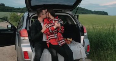 Genç çift, kız arkadaşıyla birlikte açık araba bagajında oturan, pazarlayan ve öpüşen kırsalda gezinin tadını çıkaran adam.