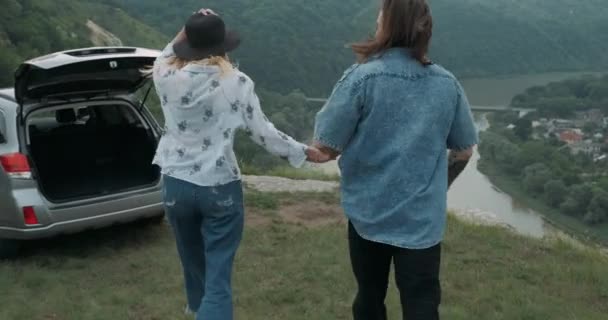 Jonge reizigers, stijlvolle man en vrouw gekleed in Boho stijl vasthouden door handen en rennen naar de rand van de rivier de Canyon, Genieten van hun Road Trip Samen, Travel Concept — Stockvideo