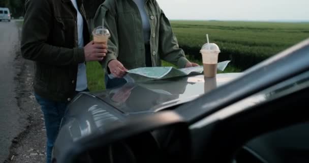 Man and Woman Using Map on the Hood of Car, Young Travelers on a Road Trip, Adventure and Travel Concept — Stock Video