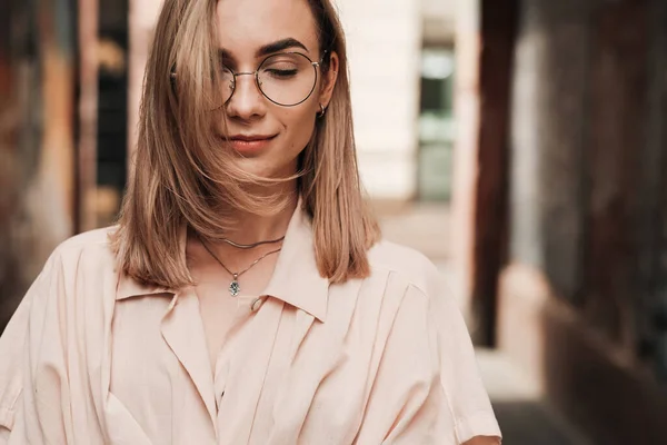 Nahaufnahme Porträt einer selbstbewussten, eleganten Frau mit Brille, die die Augen schließt, ein stilvolles blondes Mädchen mit Brille, das draußen in der Stadt steht. — Stockfoto