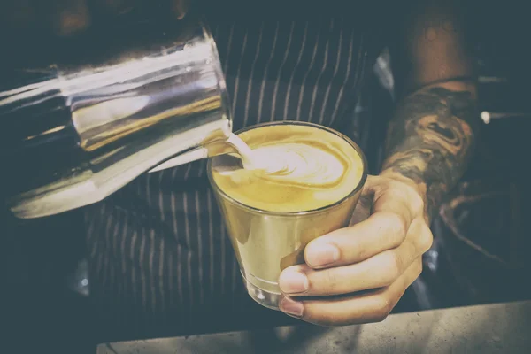 Grunge image of hand of barista making latte coffee — Stock Photo, Image