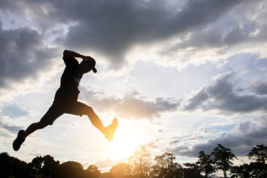 Siluet genç adam gökyüzü ve gündoğumuyla atlıyor