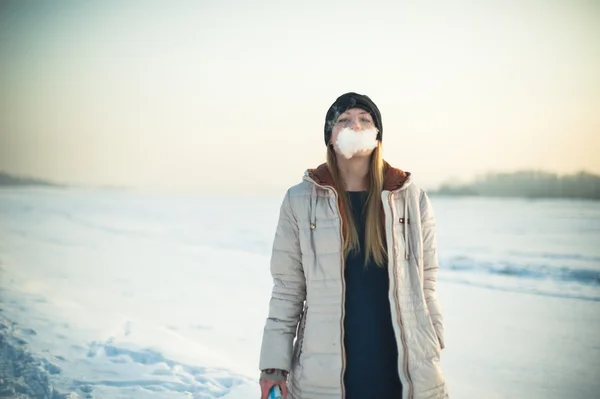 Flicka i mask röker en elektronisk cigarett — Stockfoto