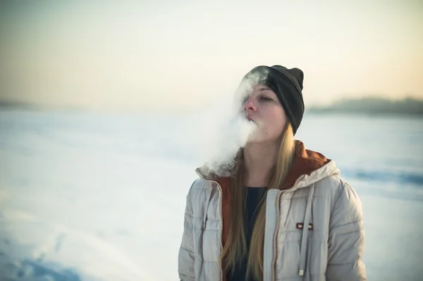 Flicka i mask röker en elektronisk cigarett — Stockfoto