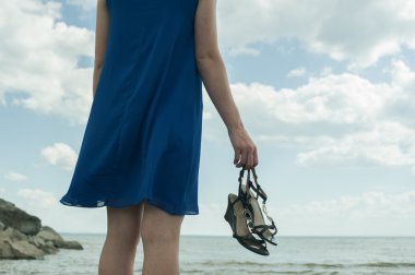 yalınayak kız sahilde ayakta ve mesafe içine görünüyor