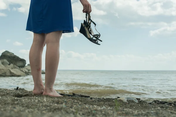 Descalza chica de pie en la playa y mira a la distancia —  Fotos de Stock