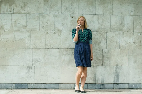 Jeune fille blonde fume cigarette électronique sur le mur de fond — Photo