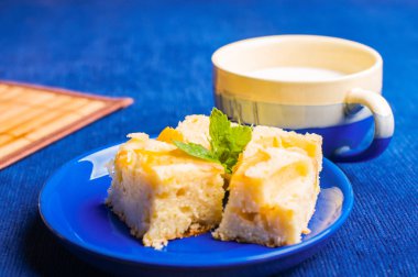 Bir bardak süt ile mavi tabakta lezzetli pasta