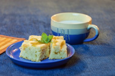 Bir bardak süt ile mavi tabakta lezzetli pasta