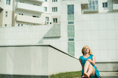 Genç sarışın kadın bacaklarını germe avluda bir bankta oturuyordu