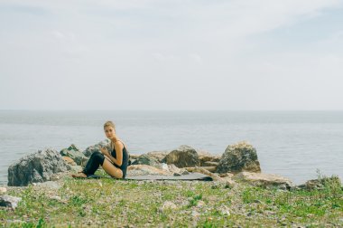 genç kadın meditasyon, germe, yoga plaj arka plan üzerinde nişanlandı