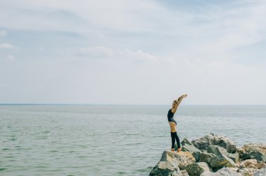 genç kadın meditasyon, germe, yoga plaj arka plan üzerinde nişanlandı
