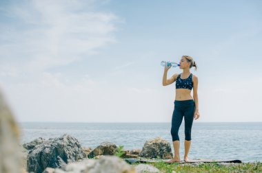 atletik kız içecekler su bir şişe bir çalışmadan sonra sahilde