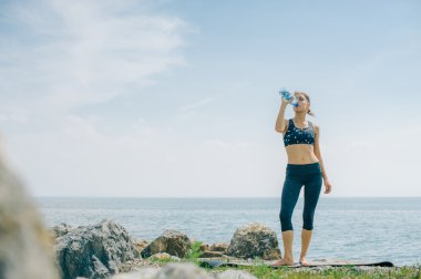 atletik kız içecekler su bir şişe bir çalışmadan sonra sahilde