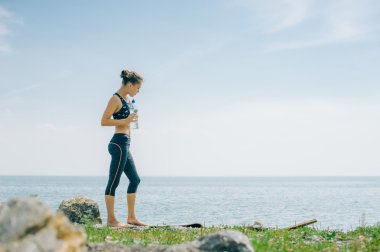 atletik kız içecekler su bir şişe bir çalışmadan sonra sahilde