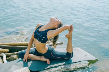 genç kadın meditasyon, germe, yoga plaj arka plan üzerinde nişanlandı