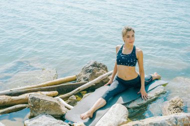 genç kadın meditasyon, germe, yoga plaj arka plan üzerinde nişanlandı