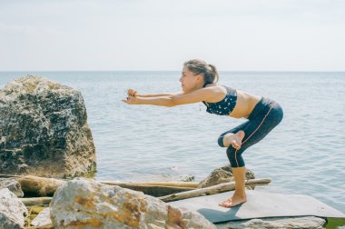 genç kadın meditasyon, germe, yoga plaj arka plan üzerinde nişanlandı