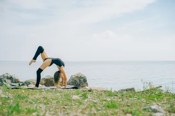 Junge Frau beschäftigt sich mit Meditation, Stretching, Yoga am Strand — Stockfoto