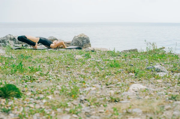 Młoda kobieta jest zaangażowany w medytacji, stretching, Joga na tle plaży — Zdjęcie stockowe