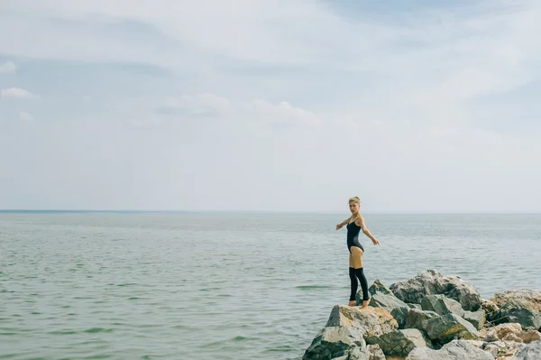 Mujer joven se dedica a la meditación, estiramiento, yoga en el fondo de la playa — Foto de Stock