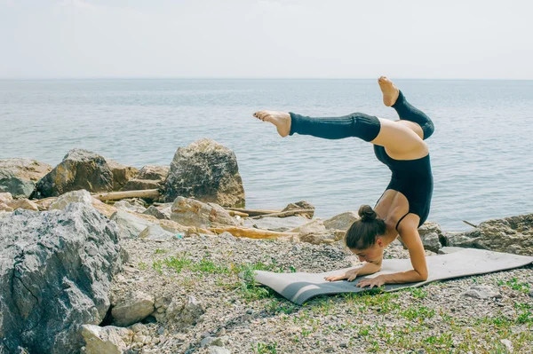 Jovem está envolvida em meditação, alongamento, ioga no fundo da praia — Fotografia de Stock