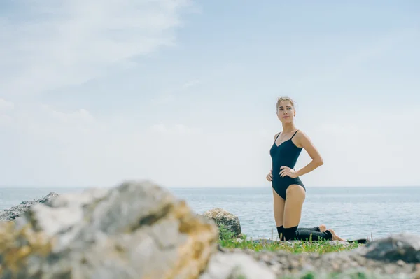 Młoda kobieta jest zaangażowany w medytacji, stretching, Joga na tle plaży — Zdjęcie stockowe