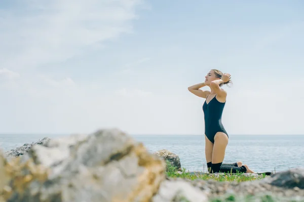 Młoda kobieta jest zaangażowany w medytacji, stretching, Joga na tle plaży — Zdjęcie stockowe