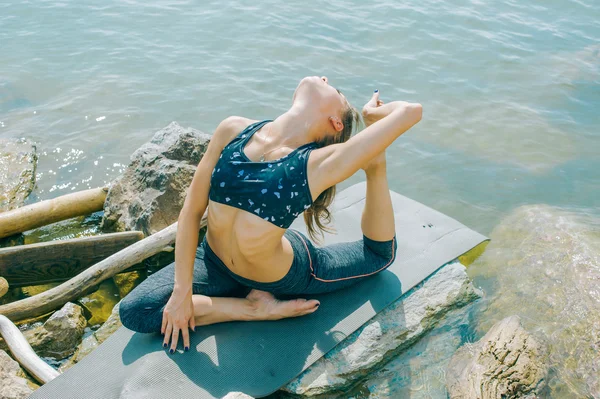 Jovem está envolvida em meditação, alongamento, ioga no fundo da praia — Fotografia de Stock