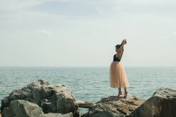 Meisje dansen op de rotsen aan de kust — Stockfoto