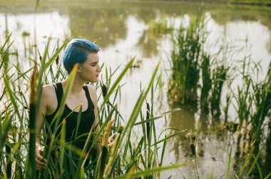 mavi saçlı genç güzel kız dik dik predator reed çalılar görünüyor