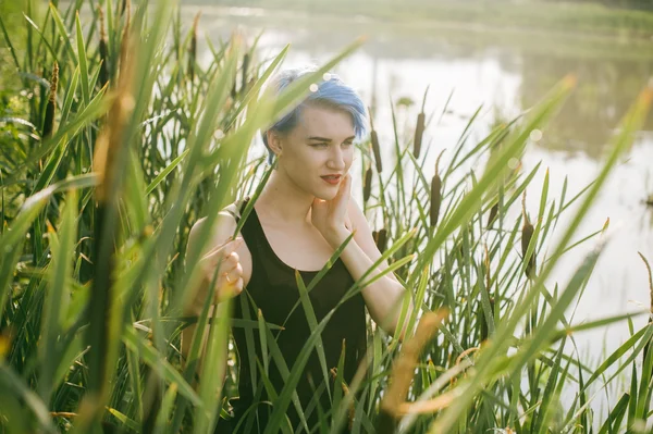 Młoda piękna dziewczyna z niebieskie włosy wygląda stare drapieżnik reed krzewów — Zdjęcie stockowe