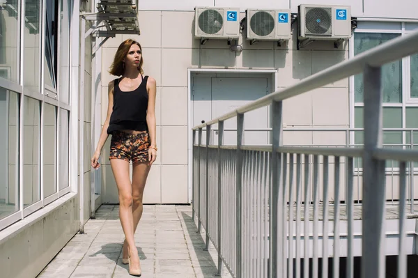 Chica joven con un hermoso cuerpo está caminando en el patio de la calle — Foto de Stock
