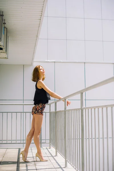 Schönes schlankes Mädchen in kurzen Hosen und T-Shirt, das auf Bolkone steht und in die Ferne blickt — Stockfoto