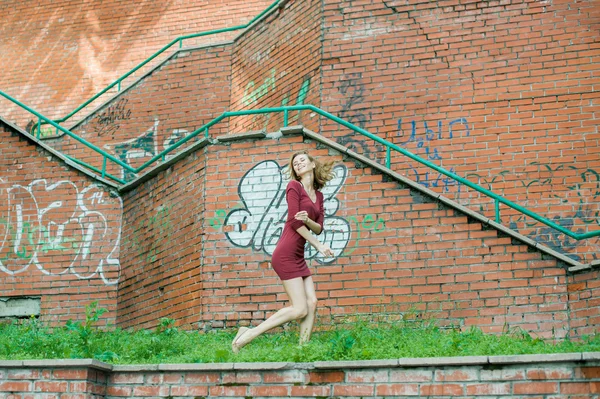 Chica acostada en la hierba sobre un fondo de una pared de ladrillo — Foto de Stock