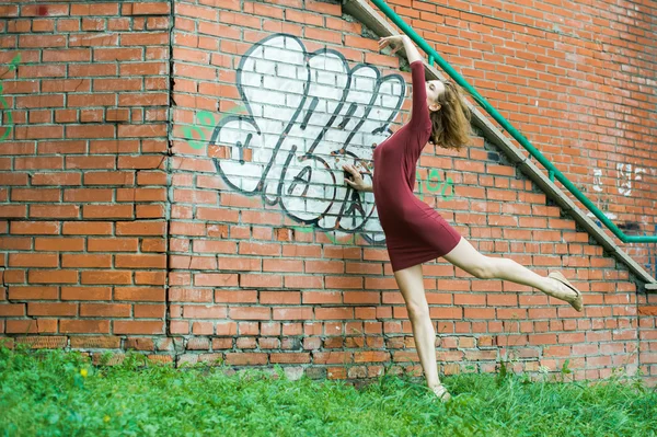 Fille couchée sur l'herbe sur un fond de mur de briques — Photo